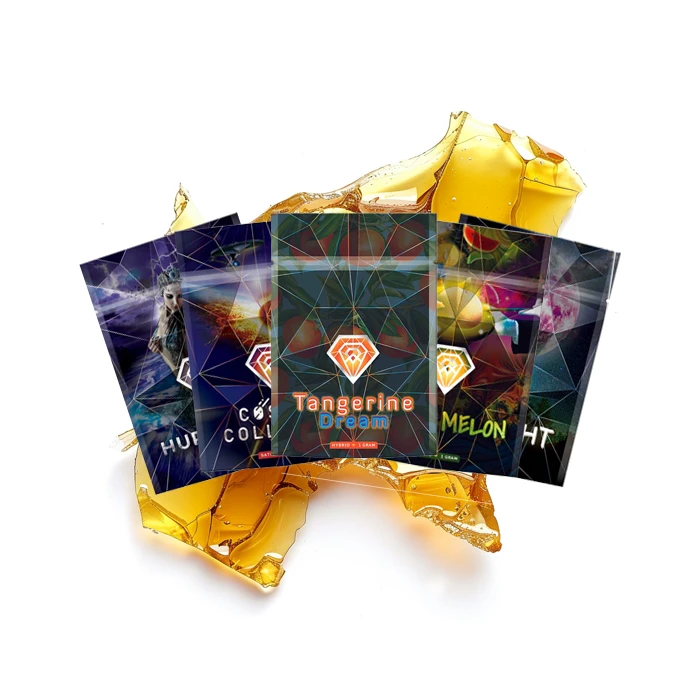 A display of five colorful packaging designs for Diamond Concentrates Shatter, laid out in a fan shape on top of a large golden-yellow slab of cannabis shatter.