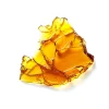 A close-up image of a solid amber-colored piece of House of Glass shatter, showing its glass-like texture and rich color, indicating purity and potency.