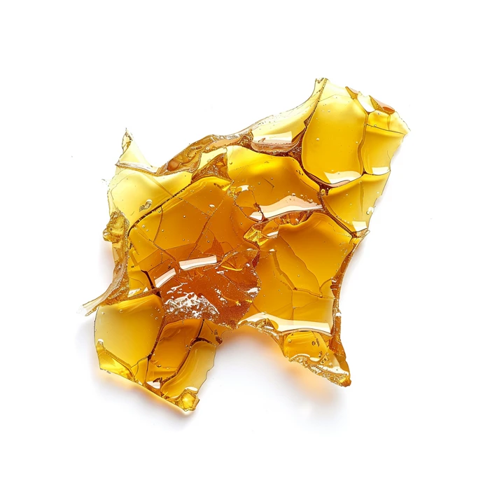 A close-up image of a piece of golden cannabis shatter, with a glossy texture and jagged edges, set against a clean white background.