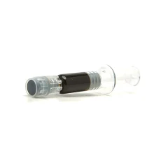 A clear plastic syringe filled with dark, viscous cherry oil, used for cannabis consumption. The syringe is lying flat, showcasing the oil inside.