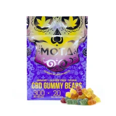 MOTA CBD Vegan Gummies package displaying vibrant purple and yellow colors with 300mg CBD per bag and 20mg per gummy. Organic, gluten-free, and vegan gummies shown with a pile of colorful gummy bears beside the package