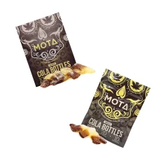 Two MOTA Cola Bottles packages with gummies displayed. One package is labeled as Sativa and the other as Indica, both containing 100mg THC and 20mg CBD. A few cola-flavored gummies are placed in front of the packages