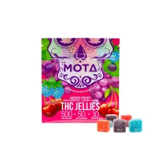A colorful package of Mota THC 500mg Edibles Gummies in mixed fruit flavor with 10 jellies. The package is vibrant, featuring illustrations of cherries, grapes, and raspberries. Five assorted gummy cubes are displayed in front of the package, representing the blue raspberry, cherry, and grape flavors. The label highlights 500mg of THC per bag and 50mg per piece.