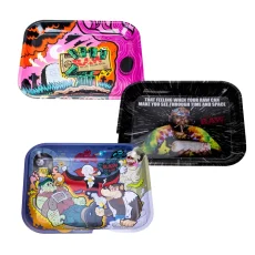 : A collection of three colorful RAW Rolling Trays. The top left tray features vibrant pink and orange artwork with rolling paper and flame motifs. The top right tray has a cosmic theme with a man in a tie-dye shirt and the text: "That feeling when your RAW can make you see through time and space." The bottom tray has cartoon-style artwork with monsters, including a vampire, Frankenstein, and a werewolf smoking in a lively scene. Each tray has rounded edges and deep walls for easy rolling.