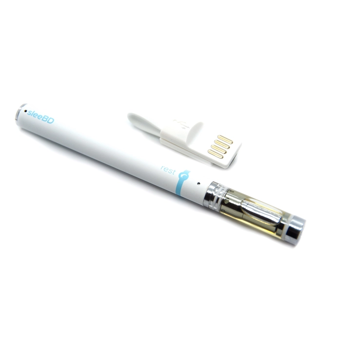 A close-up of the sleeBD Rest disposable CBD vape pen laying horizontally, next to its USB charger. The pen is white with a small blue "rest" logo and a clear cartridge showing the CBD oil inside. The pen is sleek and designed for convenience and easy use