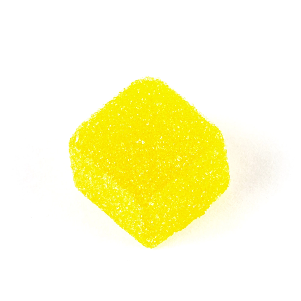 Close-up of a single yellow sour lemon gummy from Twisted Extracts' CBD Sour Lemon Twisted Singles, showcasing its sugar-coated texture