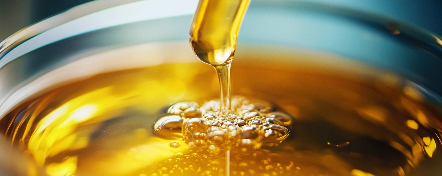 Close-up of golden cannabis oil being dropped from a pipette into a container, representing high-purity Distillate THC.