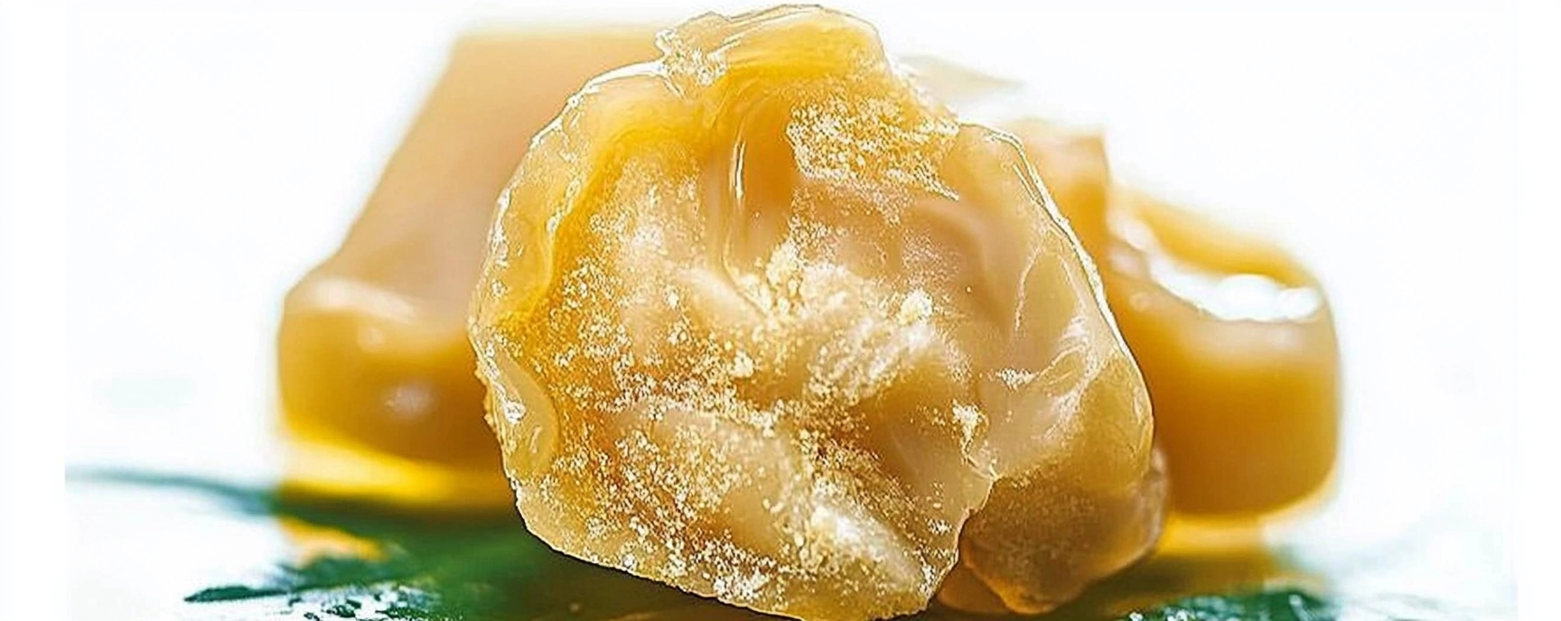 Macro shot of fresh rosin cannabis concentrate with a rich, waxy appearance and glistening surface, highlighting the pure texture of rosin available at Weed Market.