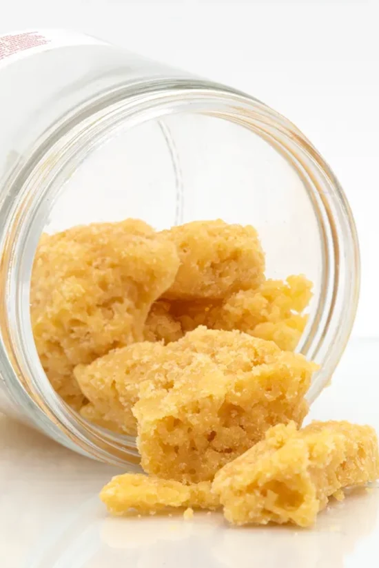 THC wax crumble from Weed Market spilling out of a glass jar, showing dry and grainy texture ideal for joints