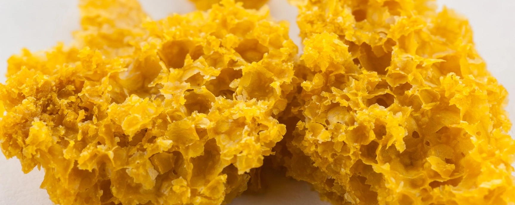 Close-up of honeycomb-style THC wax from Weed Market, with a light, airy structure and vibrant golden color