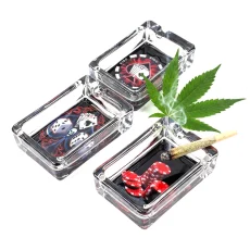 Three rectangle Royal Flush glass ashtrays with poker chip, dice and skull designs, lit cannabis joint resting on one ashtray with poker chips inside
