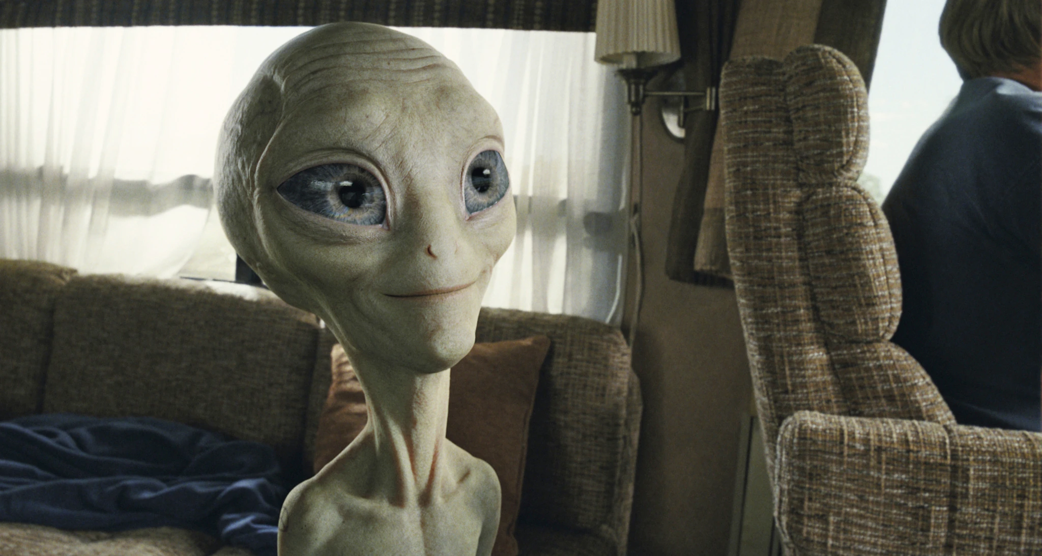 The alien Paul sits smiling in an RV armchair in the film Paul
