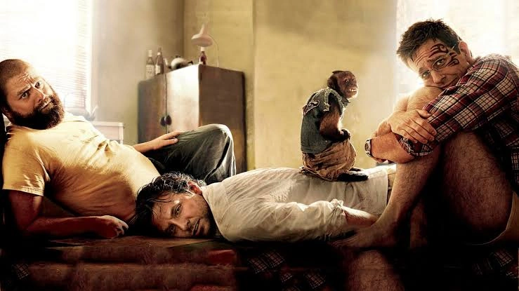 Zach Galifianakis, Bradley Cooper and Ed Helms lounge in a Vegas hotel room with a monkey in The Hangover