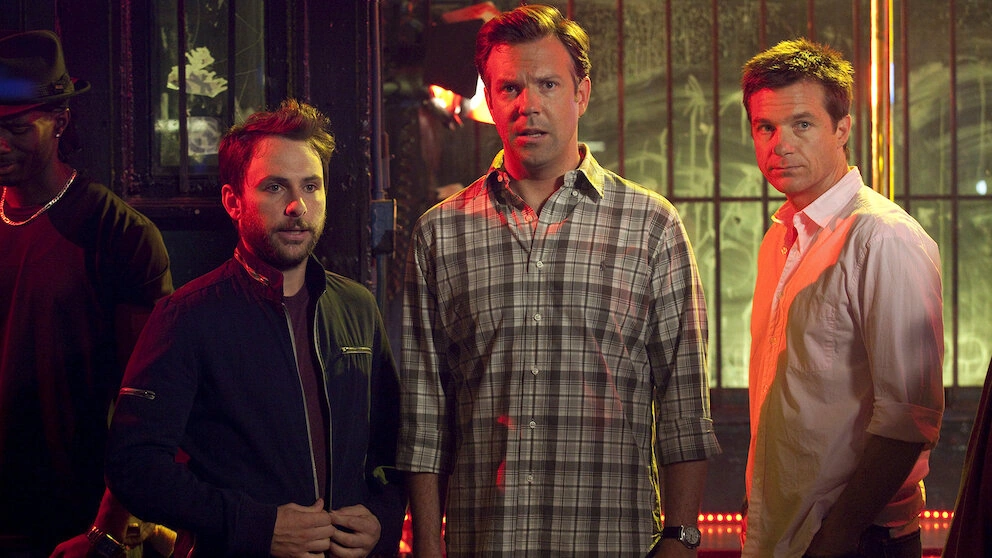 Charlie Day, Jason Sudeikis and Jason Bateman stand looking worried in a dimly lit bar in Horrible Bosses